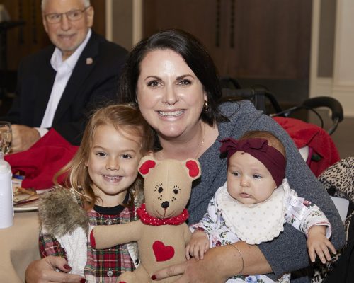 A woman and two children holding a teddy bear