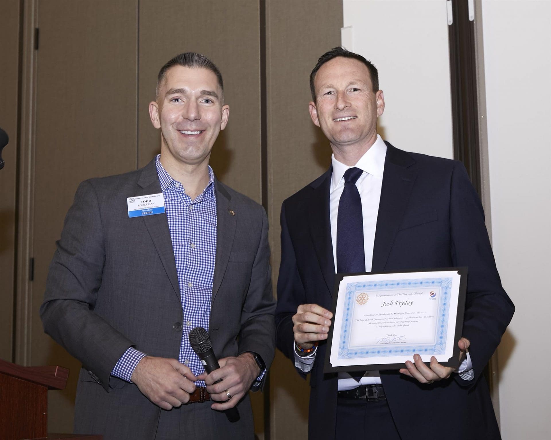 Two men, one holding an award