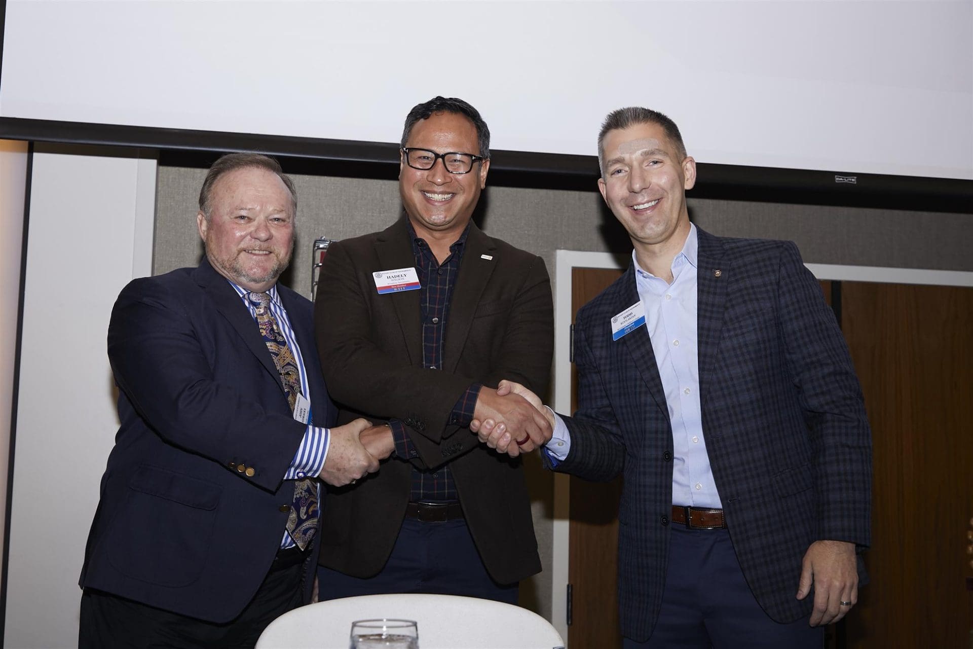3 people smiling and shaking hands