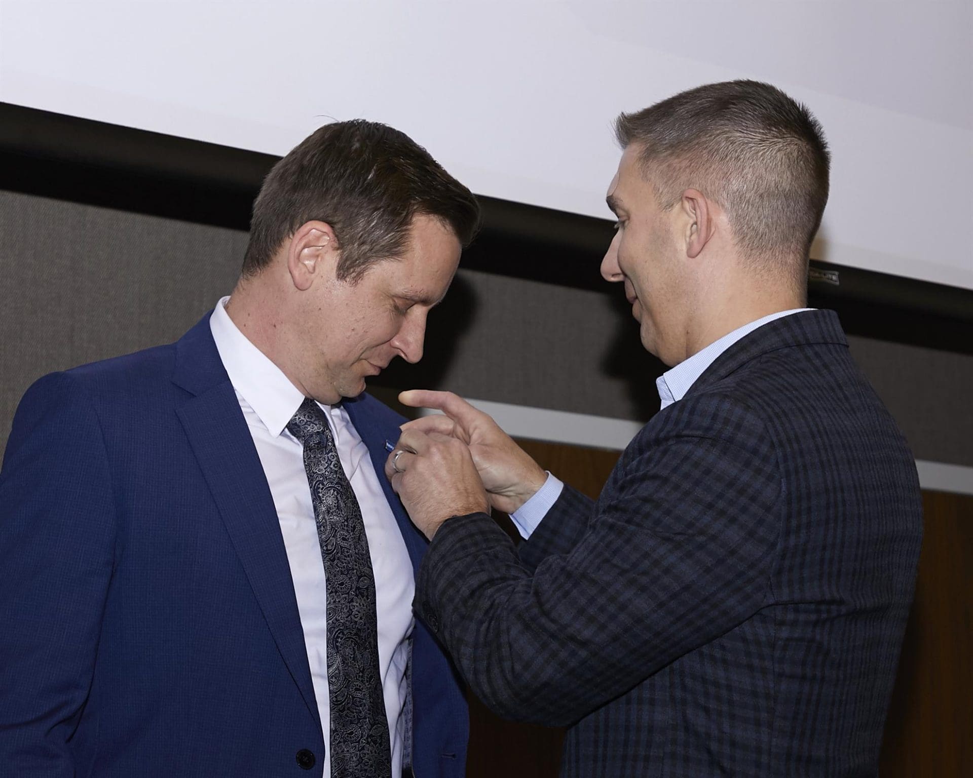 person attaching a button to another person's suit