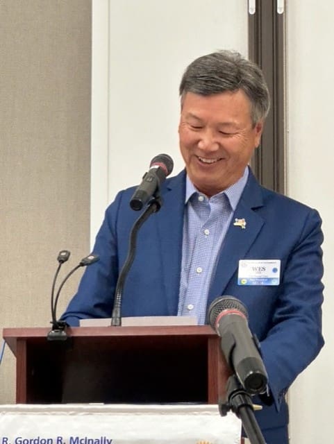 person smiling and looking down from his microphone