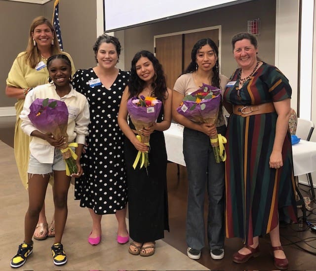 6 people smiling with 3 of them holding a basket of flowers