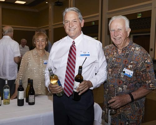 2 people smiling while 1 holds 2 bottles