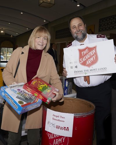 two people holding a salvation army sign and putting things into a donation bin