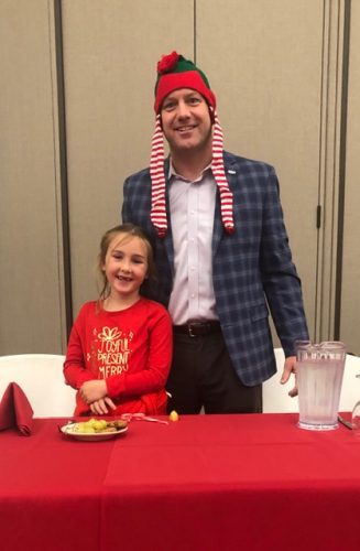 person standing behind table with a christmas themed hat