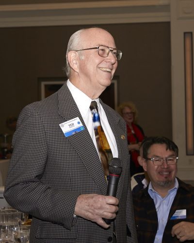 person smiling looking out in the distance while holding a microphone