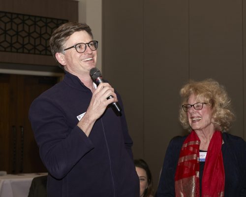 person smiling and speaking into microphone