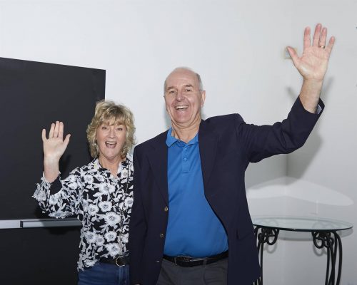 two people waving at camera