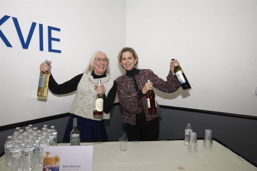 two people holding bottles at camera