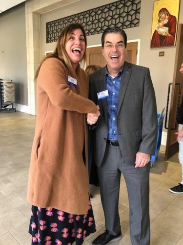 two people smiling at camera shaking hands