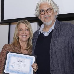 a man and a woman standing next to each other while the woman is holding a certificate/award