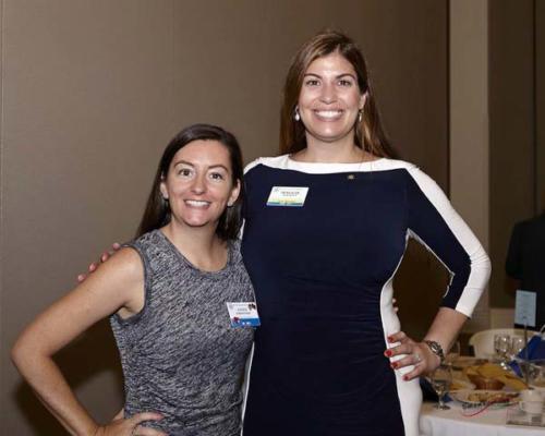 Two women in name tags smile at the camera