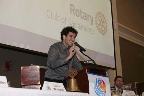 A young man talks into a microphone at a Rotary Club of Sacramento event.