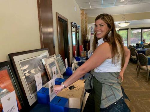 Woman smiles at camera as she places ticket in silent auction box.