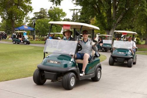 People drive a procession of golf carts in a golf course