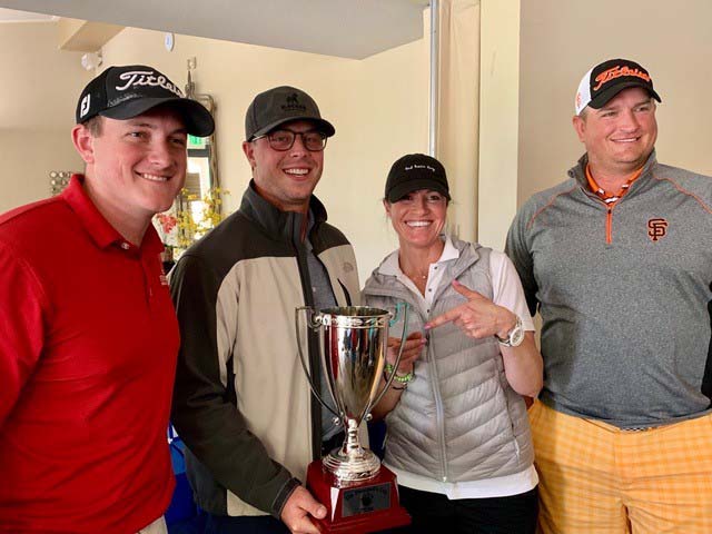 Four people pose with a trophy