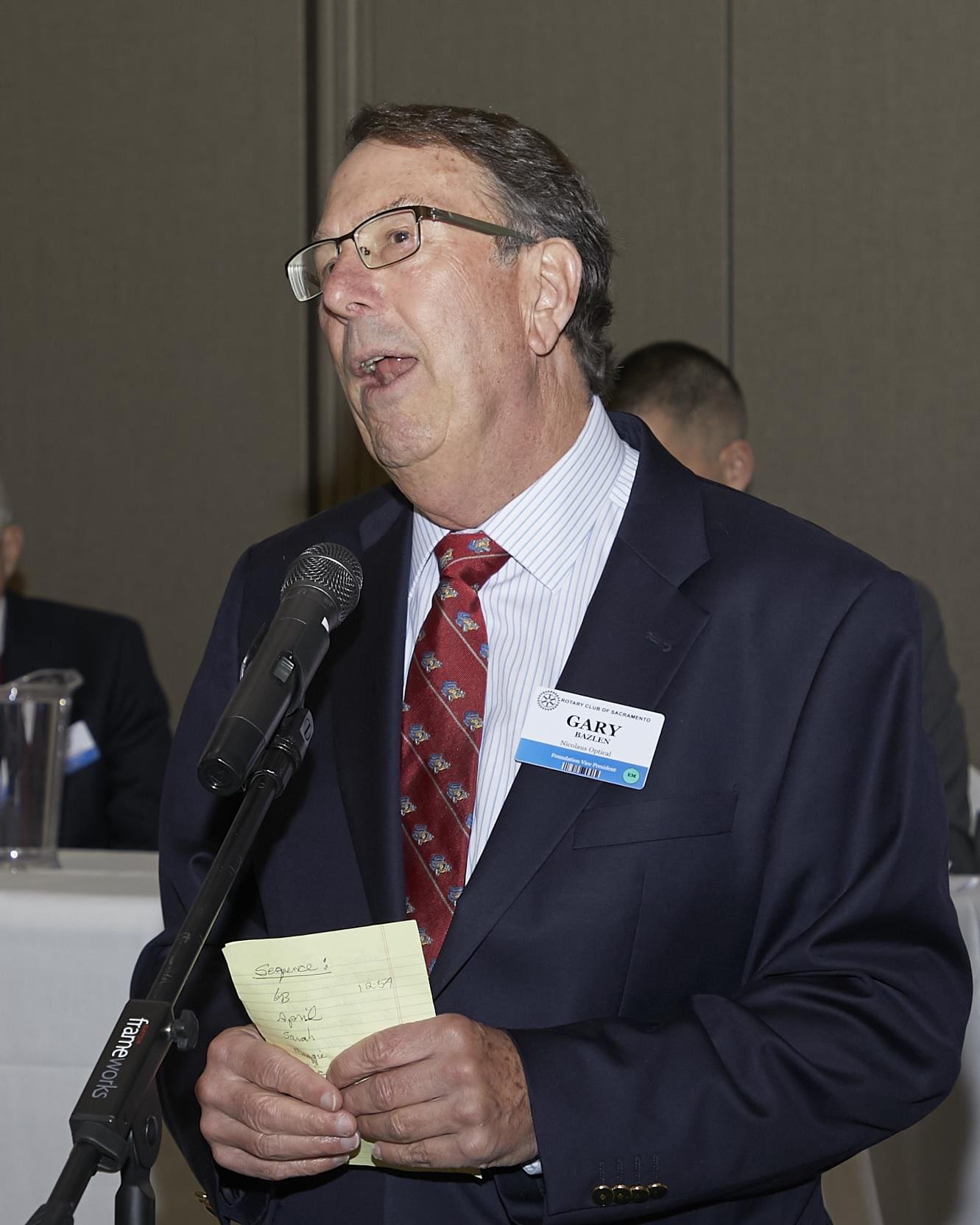 Man speaking into microphone and holding paper