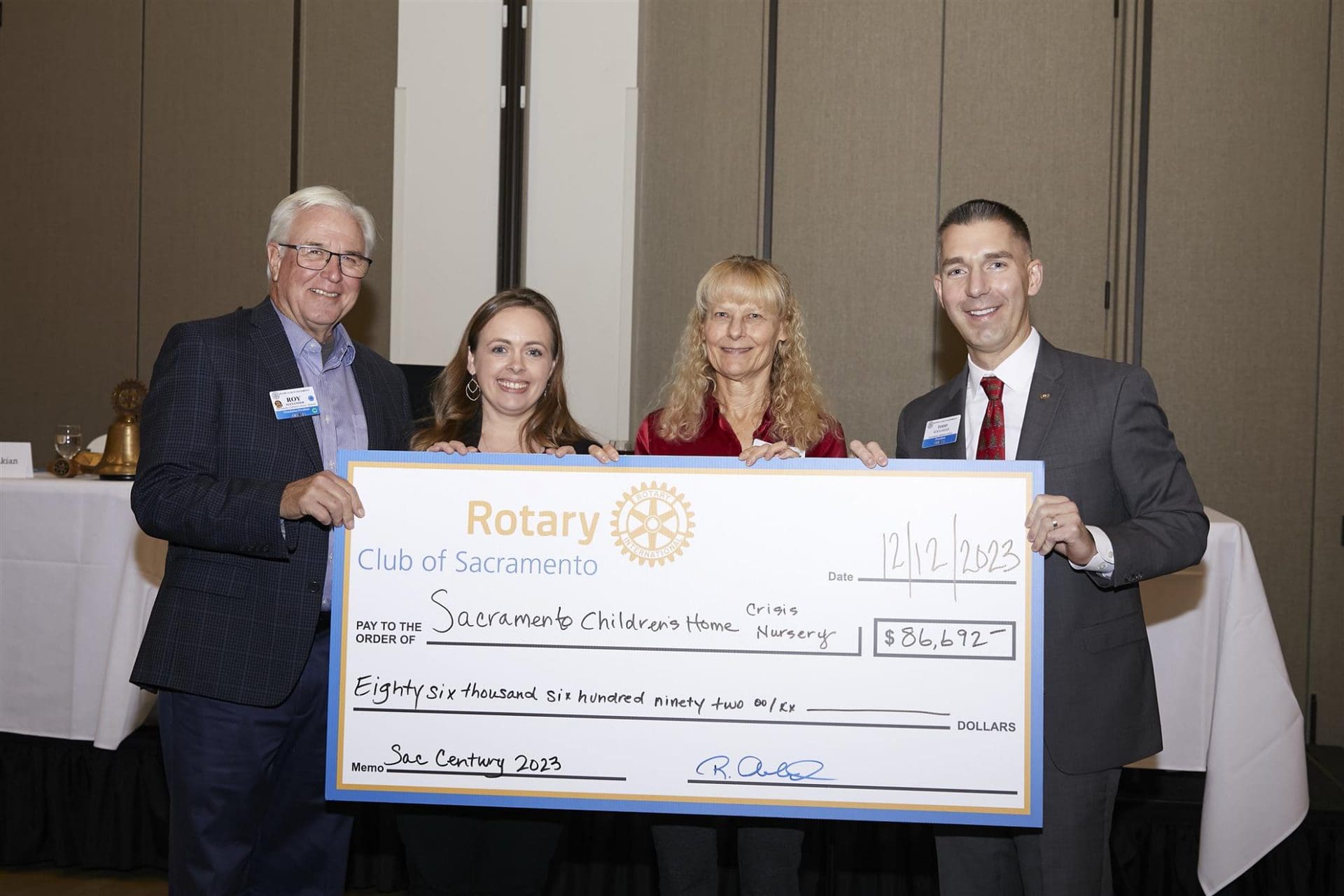 4 people posing with a big board check to Sacramento Children's Home