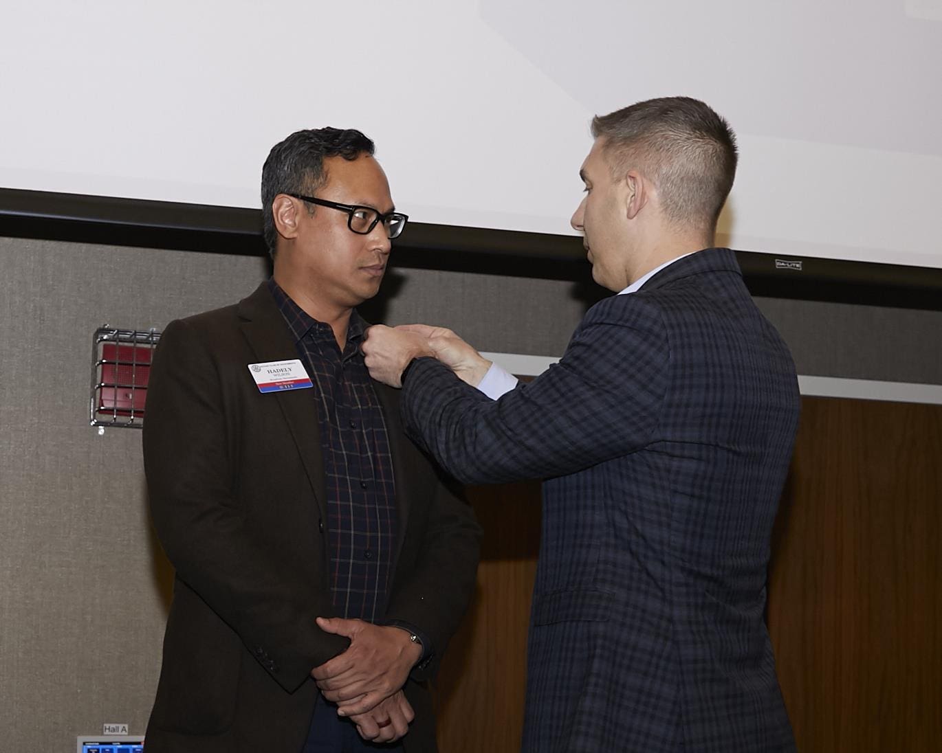 person attaching a button to another person's suit