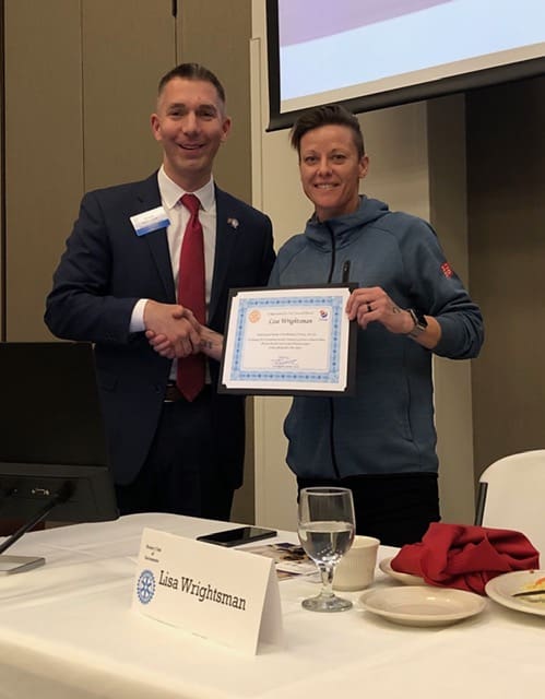 2 people smiling and holding an award