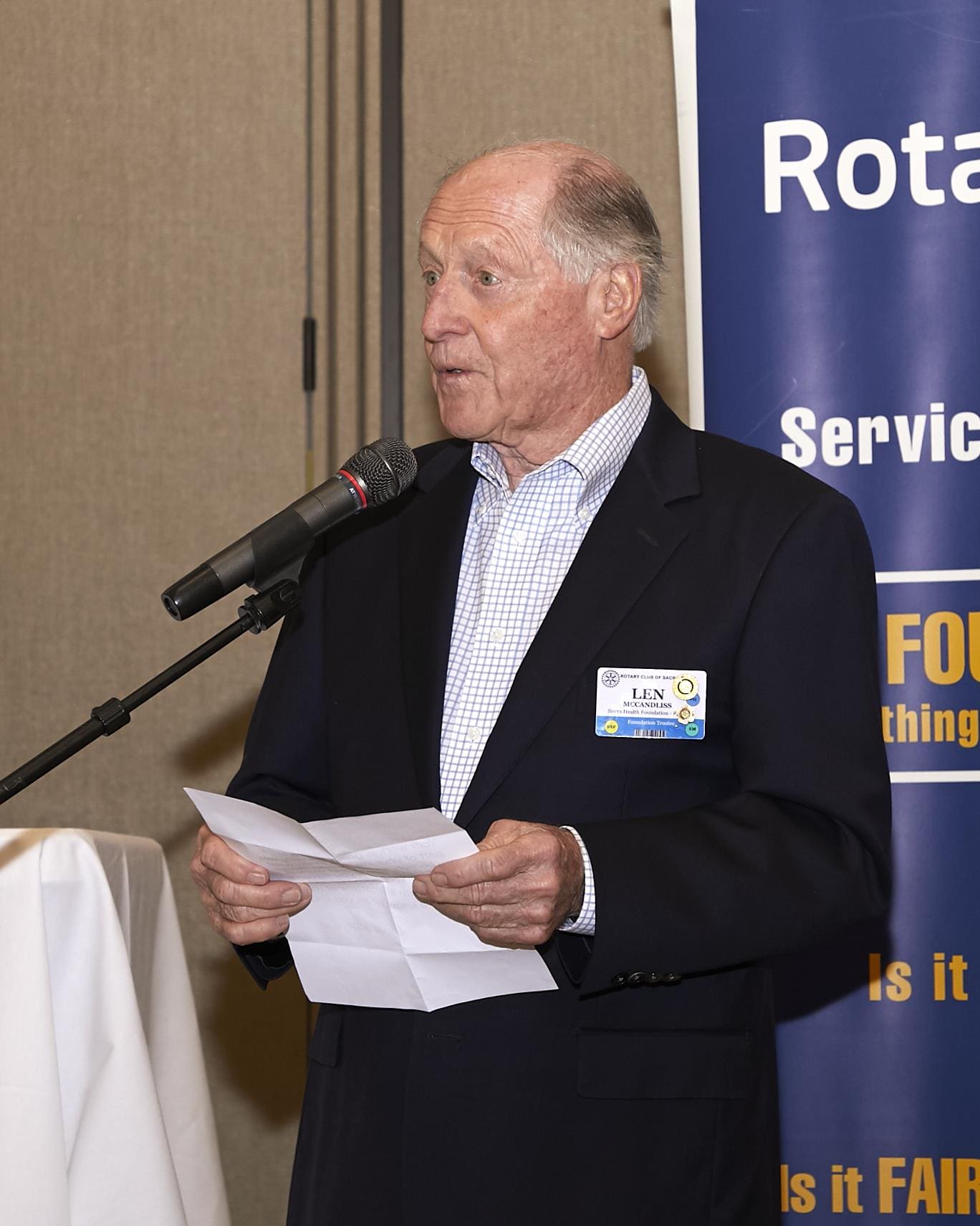 person speaking into the microphone and holding a paper