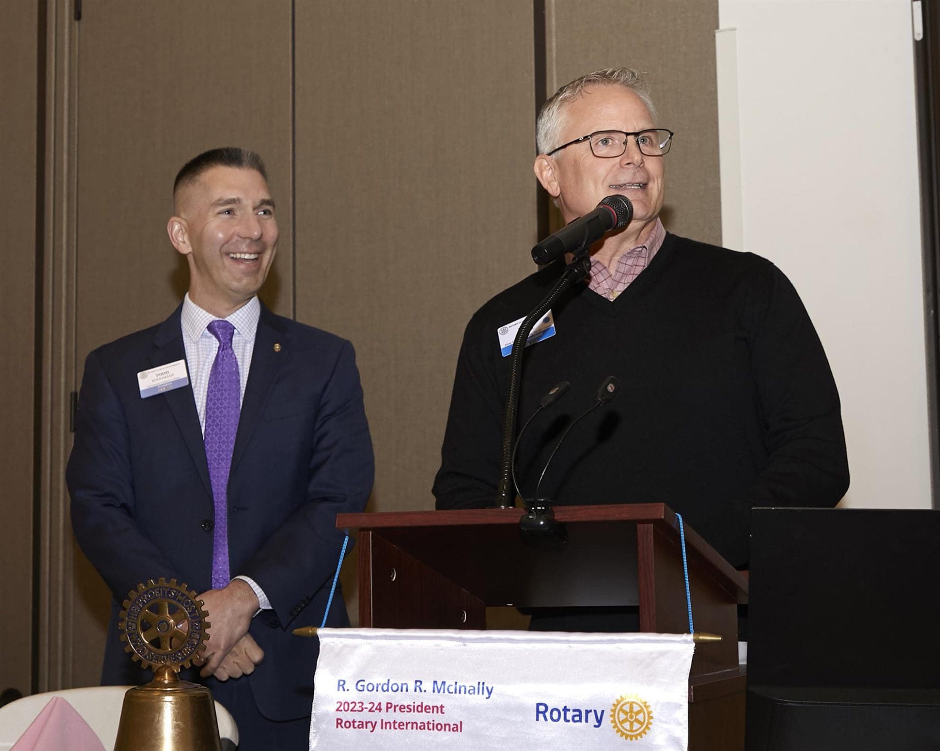 2 people smiling and 1 speaking into a microphone