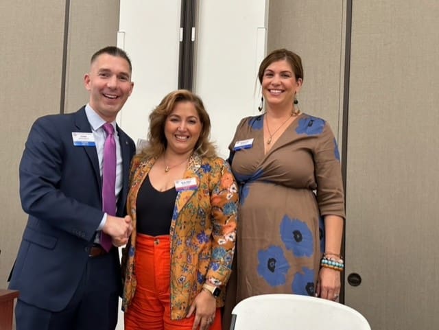 3 people smiling and 2 of them shaking hands