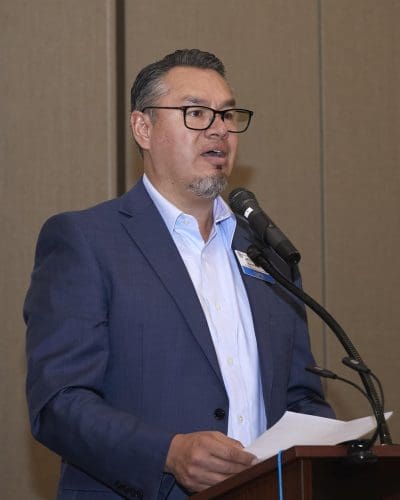 person holding a paper with both hands and speaking into a microphone