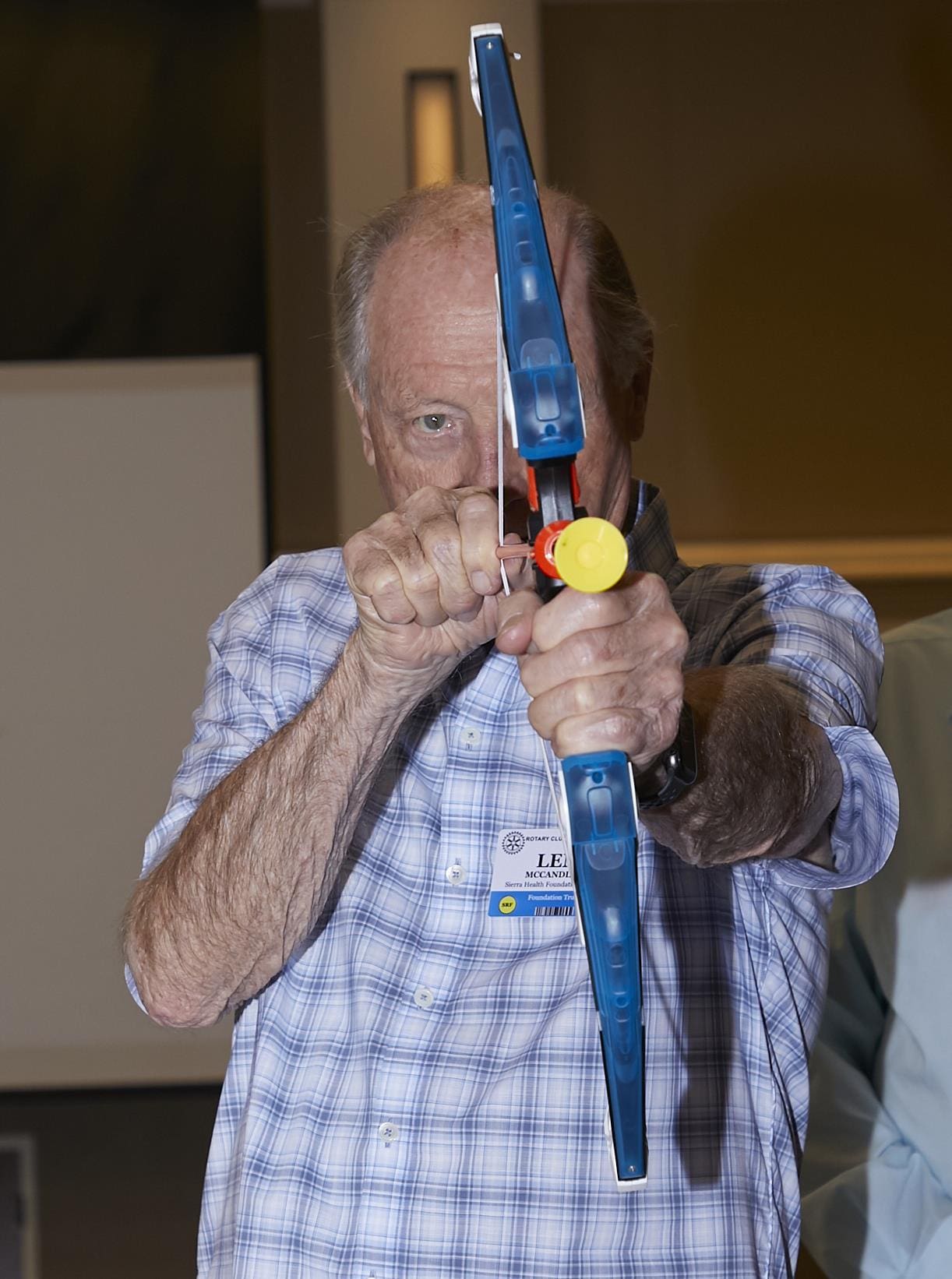 a person smiling and holding a toy bow and arrow to the camera