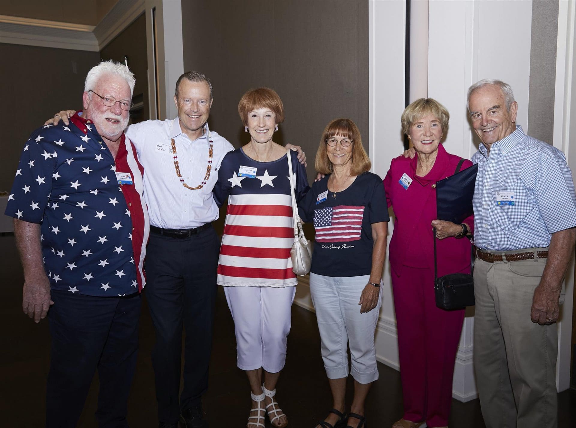 6 people smiling and wrapping their arms around each others shoulders