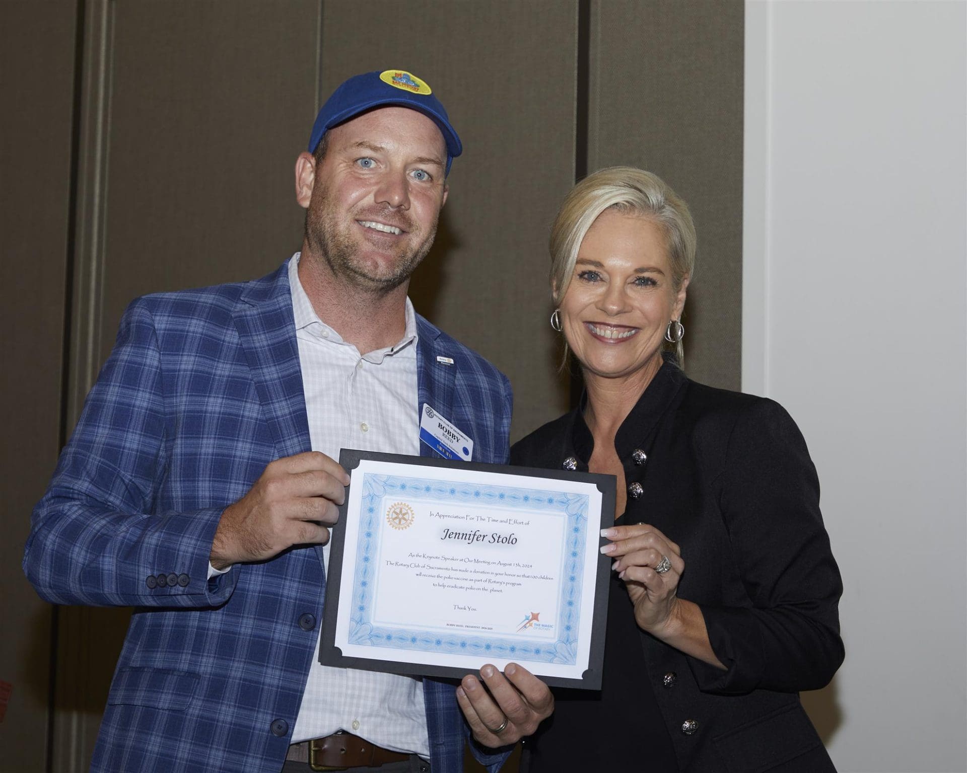 2 people holding a rotary club certificate or award