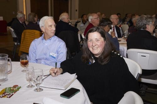 person at table writing something looking at camera