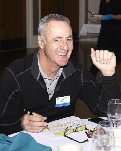 person smiling at camera and highlighting a paper on the desk