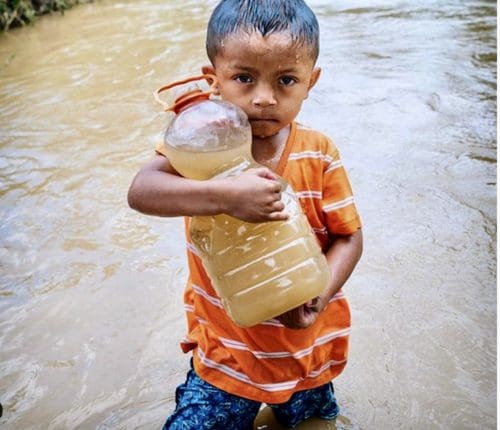 boy holding a jug of dirty water