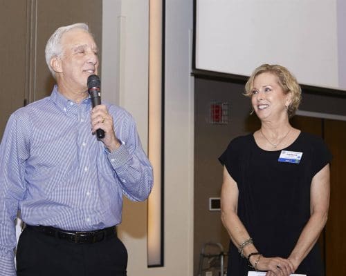 person speaking into microphone while another person looks at them