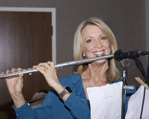 Kerry Wood holding a flute to her mouth as if to play