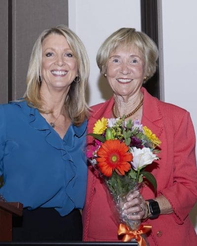 Two women holding a vase of flowers