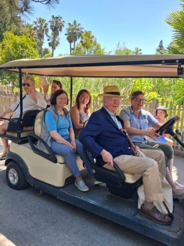 A golf cart transporting several people on a walkway at the zoo