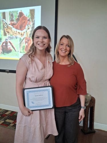 An image of two women standing close together and smiling for a photograph