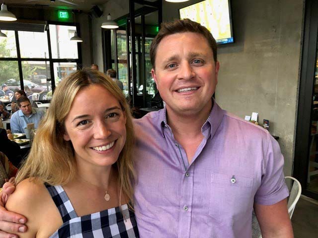 A man and woman smile at the camera in a restaurant
